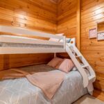 Children bedroom with bunk bed and wooden walls. Cozy and comfortable cottage interior.