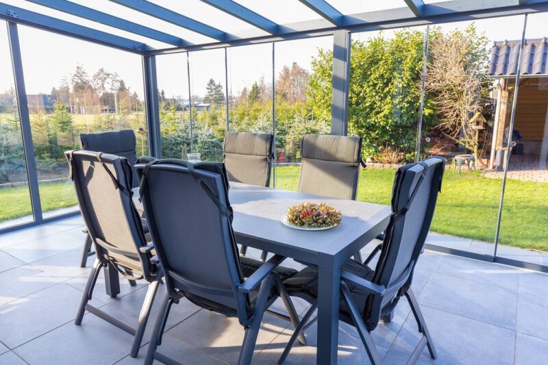 Coin repas convivial installé dans une véranda vitrée