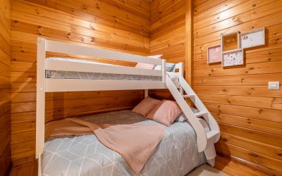 Children bedroom with bunk bed and wooden walls. Cozy and comfortable cottage interior.
